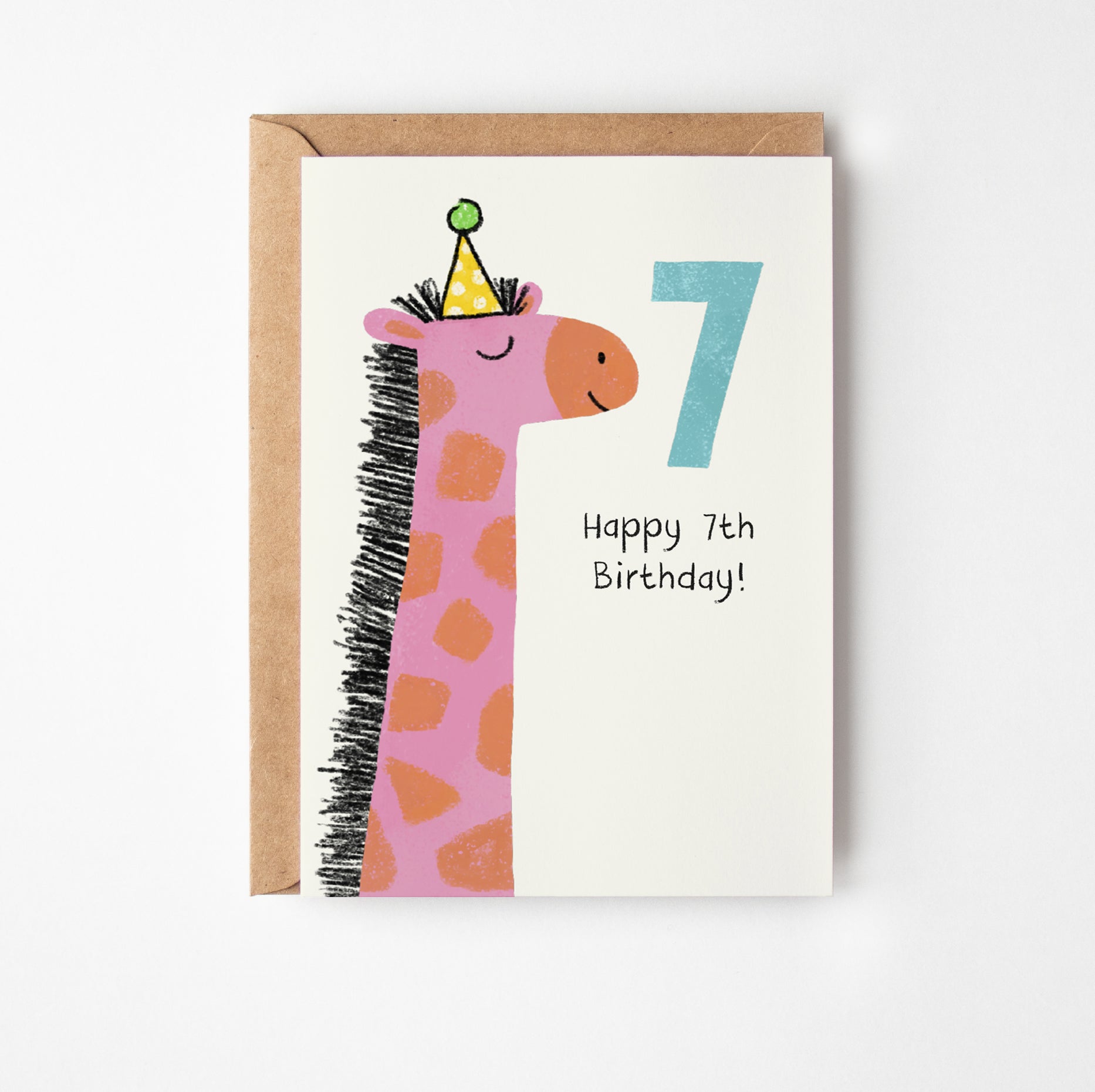 A greeting card with a kraft envelope, featuring a cute pink giraffe wearing a party hat next to a large number 7 and the text 'Happy 7th Birthday!' on a white card.
